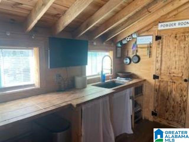 kitchen featuring lofted ceiling, wood walls, sink, and wooden ceiling