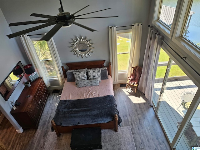 bedroom with multiple windows, wood-type flooring, and ceiling fan