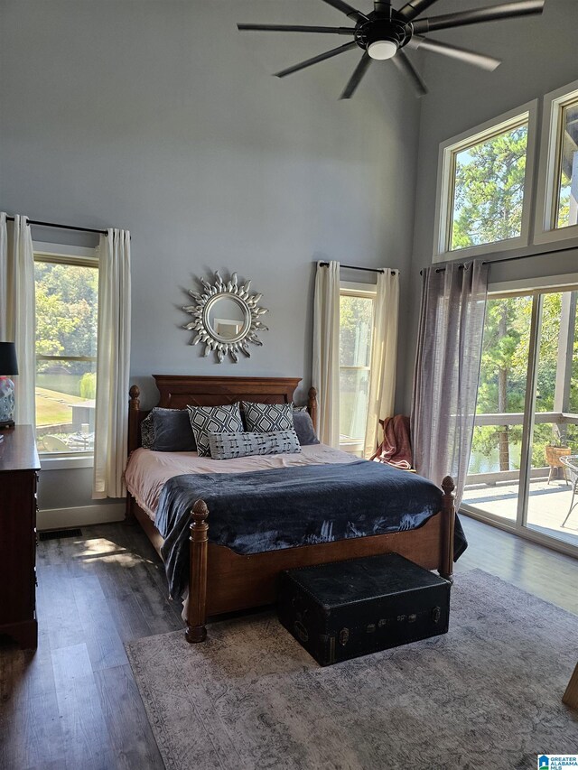 bedroom with dark wood-type flooring, ceiling fan, a towering ceiling, and access to outside