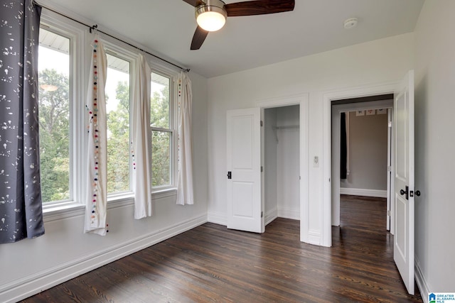 unfurnished bedroom with ceiling fan, dark wood-type flooring, and multiple windows