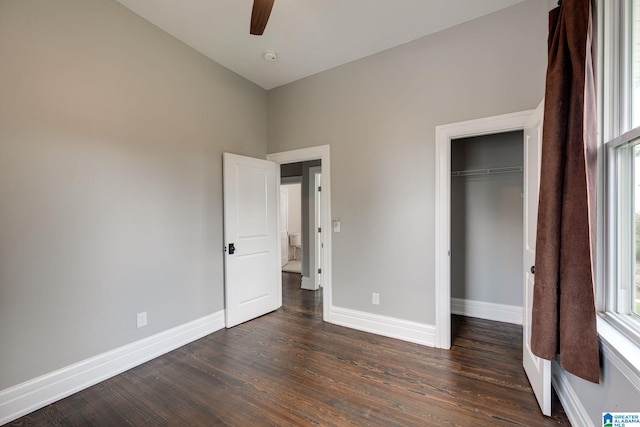 unfurnished bedroom with ceiling fan, a closet, and dark wood-type flooring