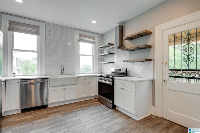 kitchen featuring a wealth of natural light, tasteful backsplash, wall chimney exhaust hood, and stainless steel appliances