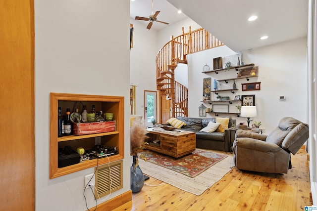 living room featuring ceiling fan, light hardwood / wood-style flooring, and a high ceiling