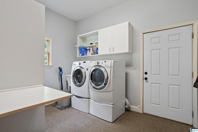 clothes washing area featuring separate washer and dryer and cabinets