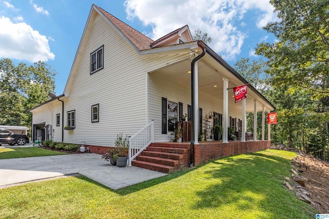 rear view of house with a lawn, covered porch, and a garage