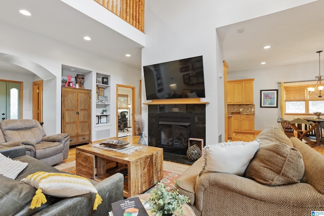 living room with a wealth of natural light, built in features, light hardwood / wood-style floors, and a chandelier