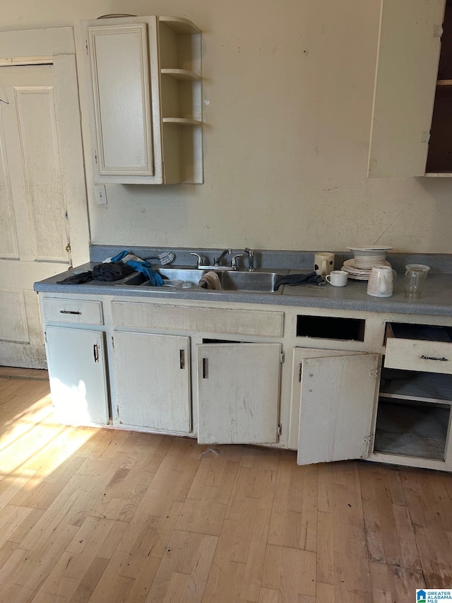 kitchen with light wood-type flooring, white cabinetry, a sink, and open shelves