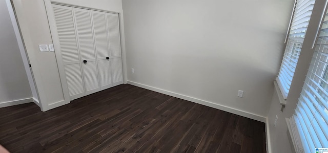 unfurnished bedroom with a closet and dark hardwood / wood-style flooring