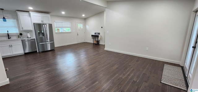 kitchen with dark hardwood / wood-style flooring, pendant lighting, stainless steel appliances, sink, and white cabinets