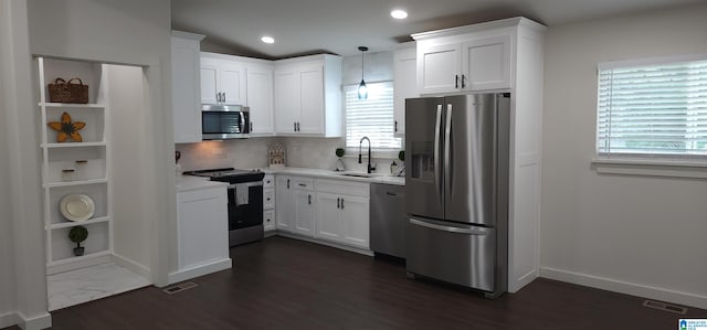 kitchen with appliances with stainless steel finishes, white cabinetry, vaulted ceiling, and pendant lighting