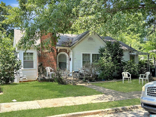 view of front of property with brick siding, a front lawn, and roof with shingles