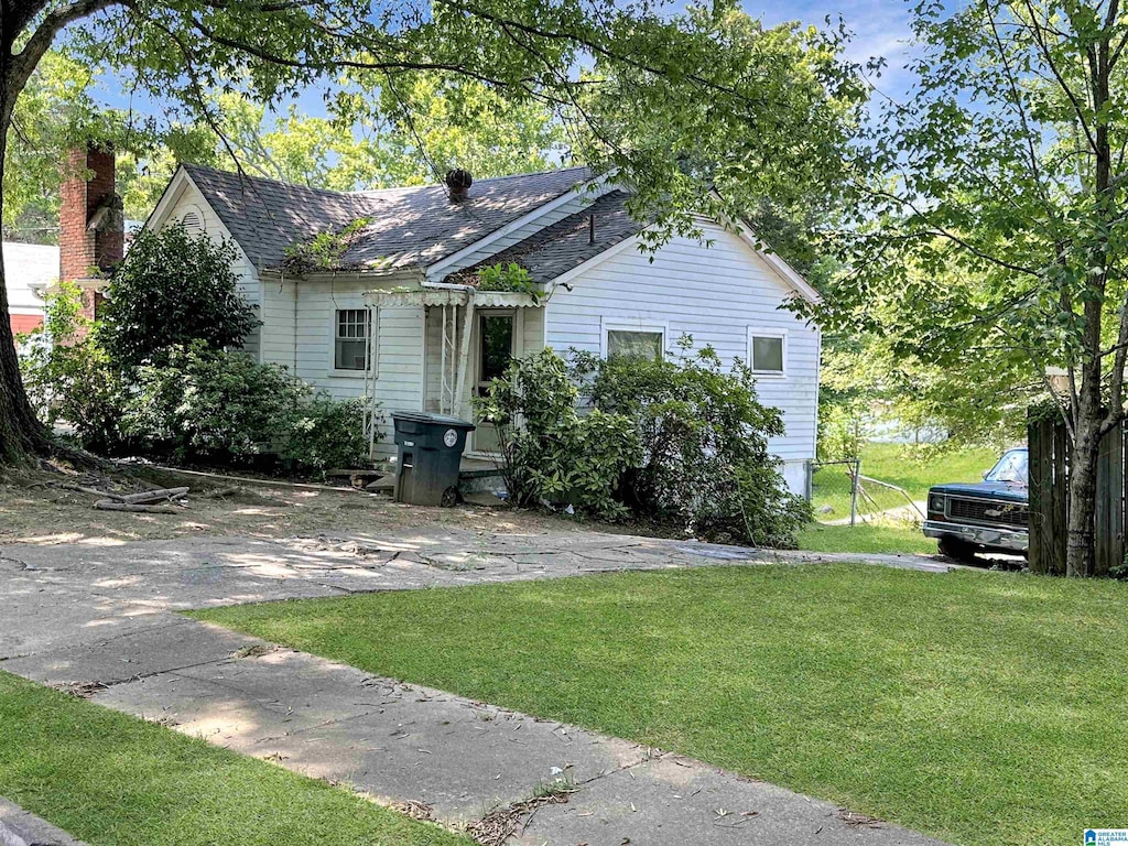 view of front of property with a front yard and a shingled roof