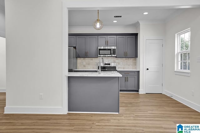 kitchen with stainless steel appliances, decorative backsplash, light wood finished floors, decorative light fixtures, and crown molding