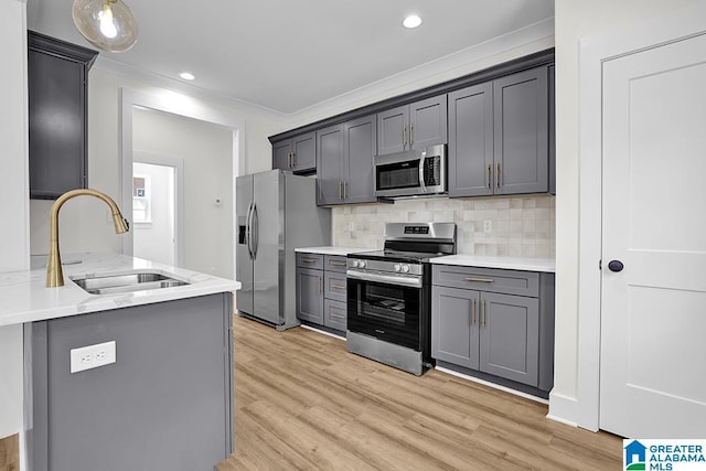 kitchen with gray cabinets, ornamental molding, stainless steel appliances, and a sink