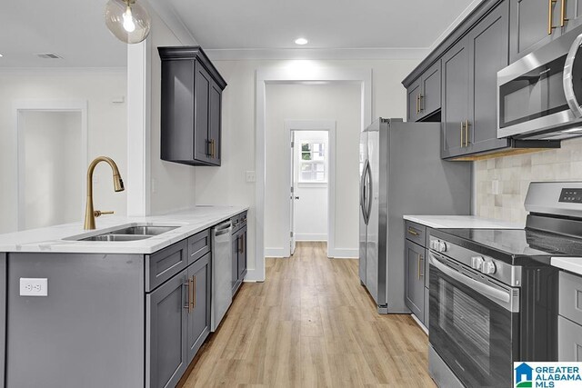 kitchen featuring decorative backsplash, light hardwood / wood-style flooring, gray cabinets, appliances with stainless steel finishes, and crown molding