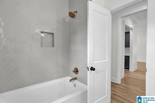 full bathroom featuring washtub / shower combination, baseboards, and wood finished floors