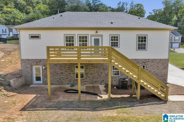 back of house featuring stairs, brick siding, and a shingled roof