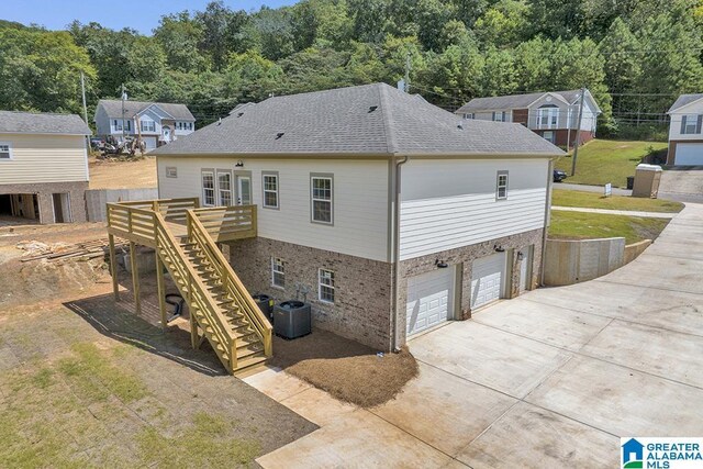 back of house with a garage, a yard, and central AC unit