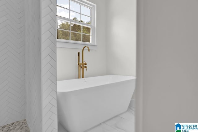 bathroom featuring marble finish floor and a soaking tub