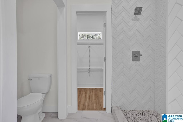 bathroom with toilet, wood-type flooring, and tiled shower