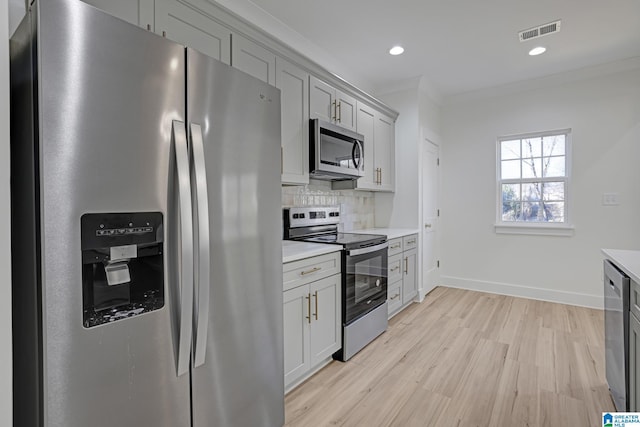 kitchen with light hardwood / wood-style flooring, gray cabinetry, stainless steel appliances, ornamental molding, and decorative backsplash