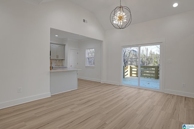 unfurnished living room featuring an inviting chandelier, vaulted ceiling, and light hardwood / wood-style floors