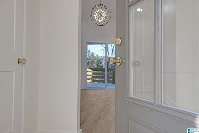 doorway featuring an inviting chandelier and light hardwood / wood-style floors