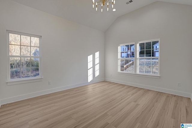 unfurnished room with an inviting chandelier, lofted ceiling, light hardwood / wood-style flooring, and plenty of natural light