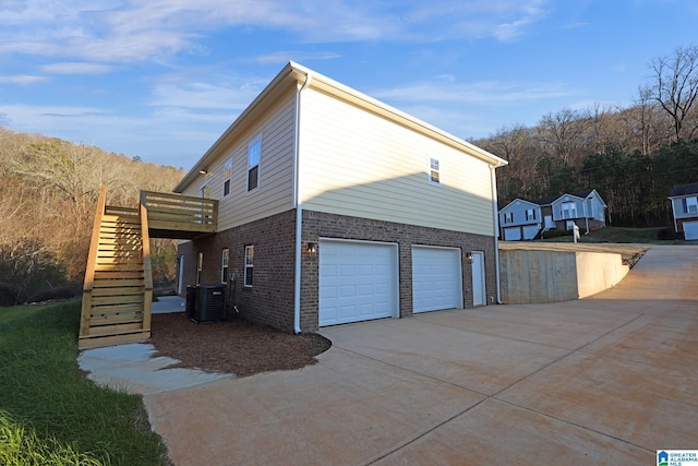 view of property exterior with a garage, a wooden deck, and cooling unit