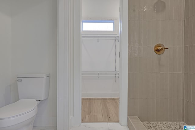 bathroom with a tile shower and toilet