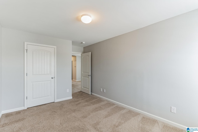 unfurnished bedroom with light colored carpet and a closet