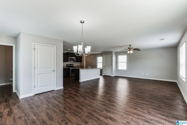 unfurnished living room with ceiling fan with notable chandelier and dark hardwood / wood-style flooring