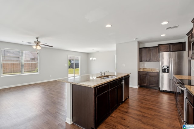 kitchen with sink, appliances with stainless steel finishes, dark wood-type flooring, ceiling fan with notable chandelier, and a center island with sink