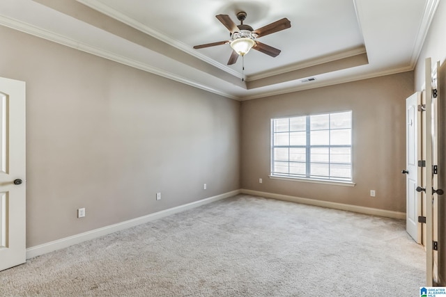 spare room featuring ceiling fan, a raised ceiling, crown molding, and light carpet