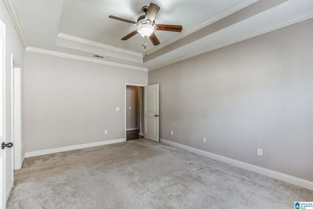 empty room with ceiling fan, light carpet, a tray ceiling, and ornamental molding