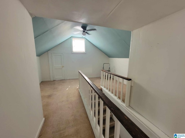 hall with vaulted ceiling and light colored carpet