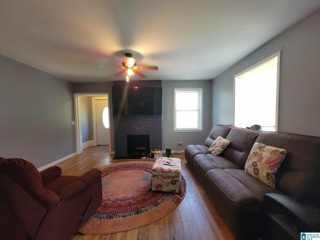 living room featuring ceiling fan, a brick fireplace, hardwood / wood-style floors, and brick wall