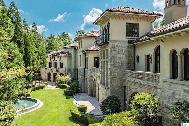 back of house with a balcony and a lawn