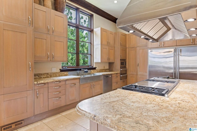 kitchen with appliances with stainless steel finishes, island range hood, sink, light stone countertops, and light tile patterned floors