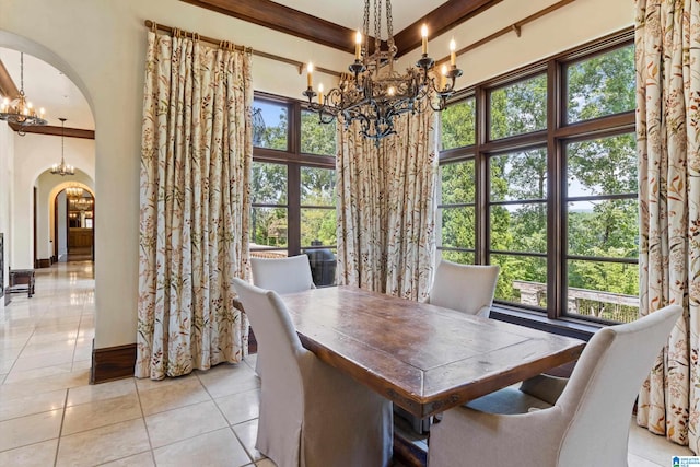 tiled dining space with beam ceiling, a high ceiling, and a chandelier