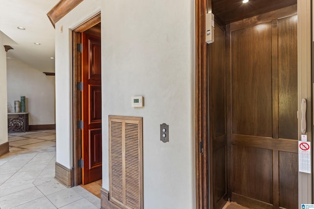 corridor featuring elevator and light tile patterned floors