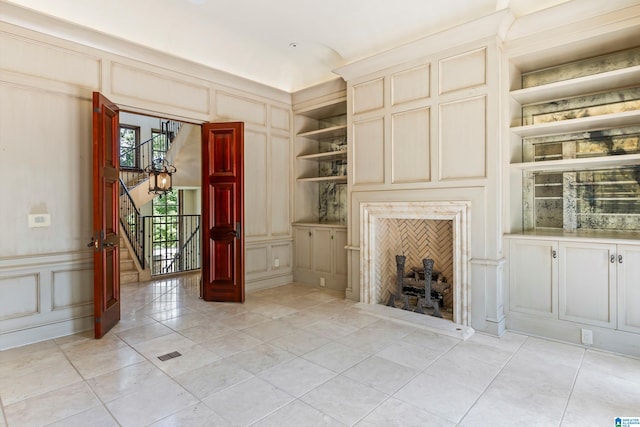 unfurnished living room with light tile patterned floors and built in shelves