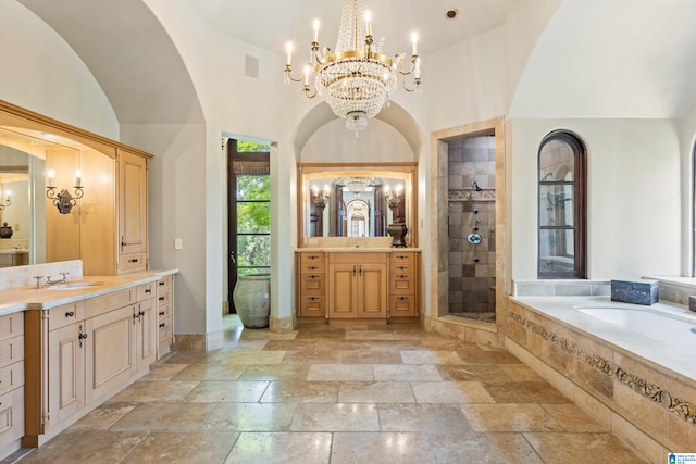 bathroom with plus walk in shower, an inviting chandelier, dual bowl vanity, and tile patterned floors