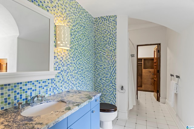 bathroom featuring decorative backsplash, vanity, tile patterned flooring, tile walls, and toilet