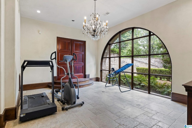 workout room with a chandelier and light tile patterned floors