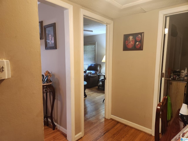 hall with a textured ceiling and light hardwood / wood-style flooring