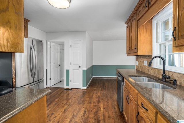 kitchen featuring backsplash, sink, dark stone countertops, appliances with stainless steel finishes, and dark hardwood / wood-style floors