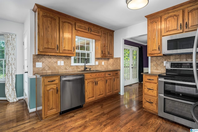 kitchen featuring backsplash, stainless steel appliances, sink, dark stone counters, and dark wood-type flooring