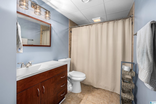 bathroom with tile patterned flooring, vanity, a paneled ceiling, and toilet