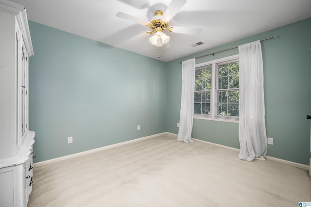 empty room featuring ceiling fan and light carpet